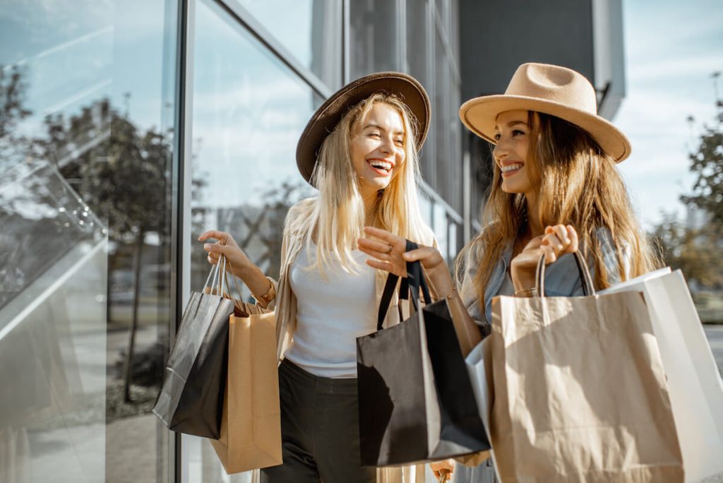 Two girls wearing hats holding shopping bags